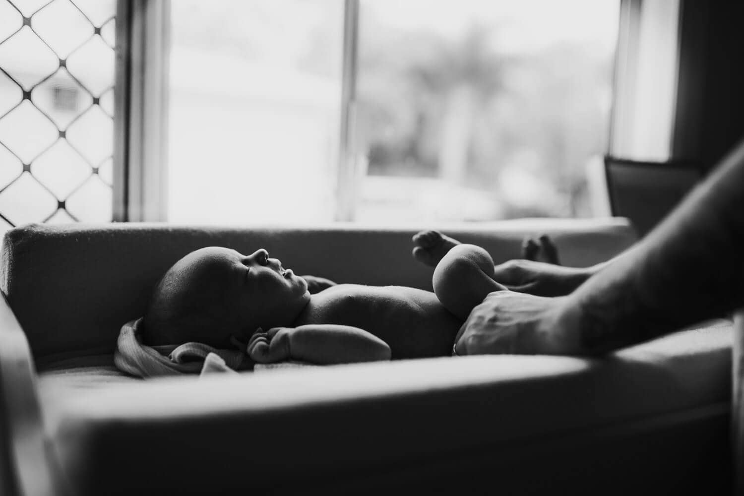 A black and white image of a newborn lying on a change table.