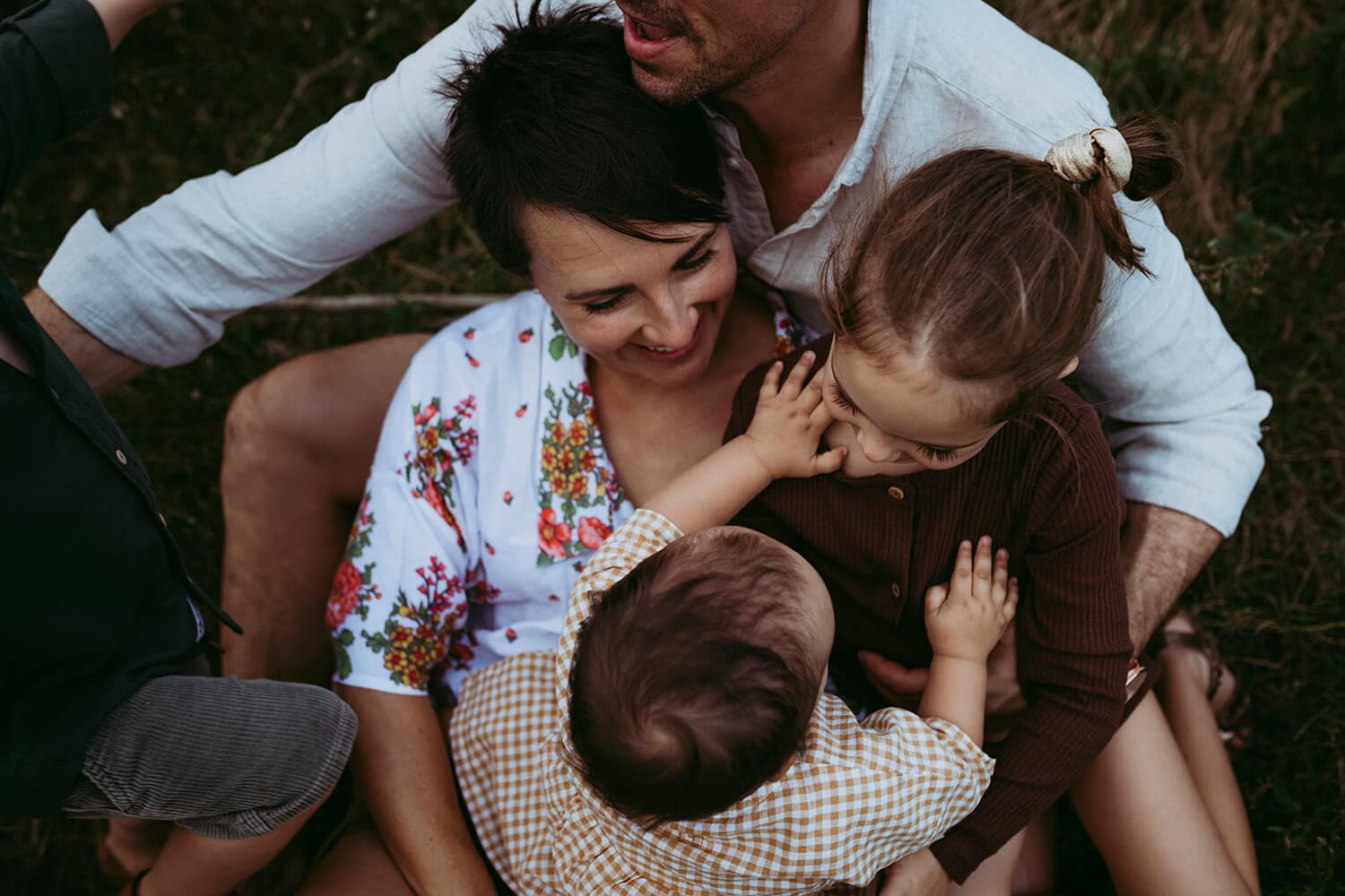 Looking at a family of five from above. A toddler reaches out for her older sister.