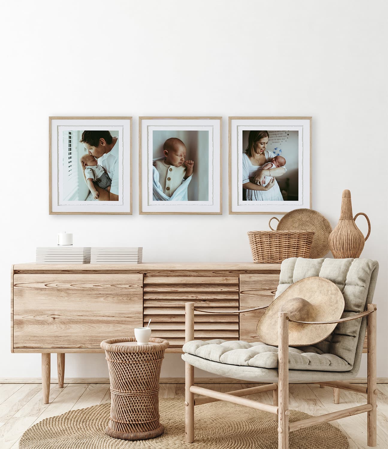 A set of three frames hangs on the wall with photos of a newborn baby in them.