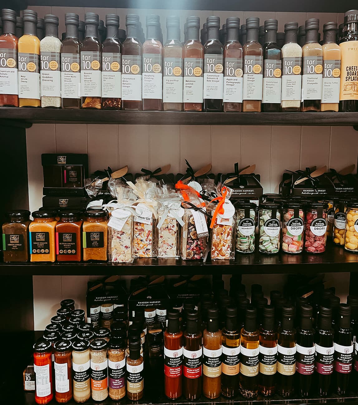 black shelves with bottles of preserves, oils and jams.