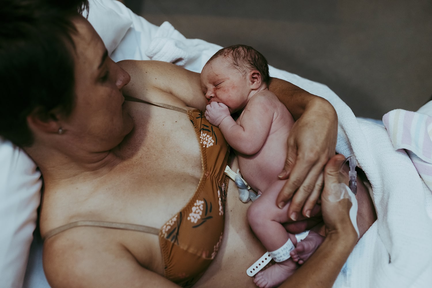 A toddler being held by her mother. They are surrounded by blue sky. The camera is angled up so you cannot see any ground. 