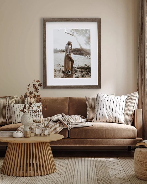 A photo is framed of a pregnant woman hangs above a brown couch.