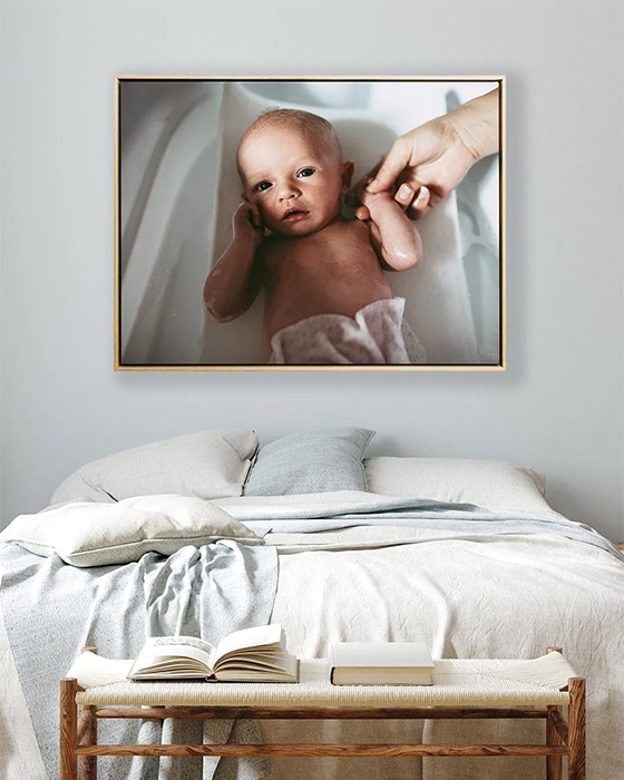 A framed canvas hangs above a large bed with a linen doona cover on it.