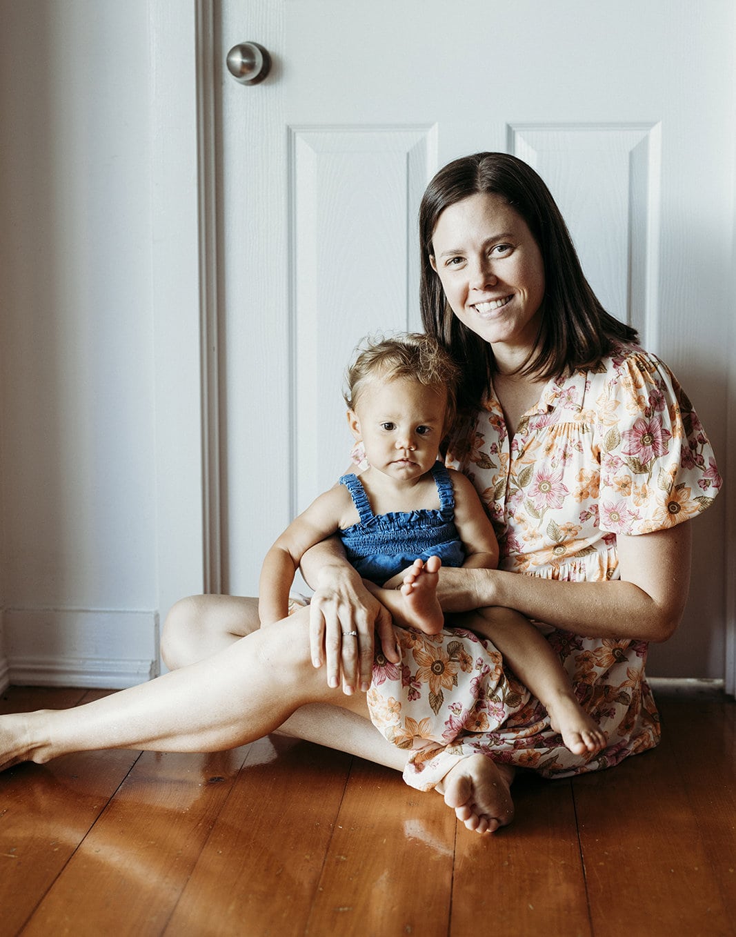 A toddlers sits in her mother's lap and smiles.