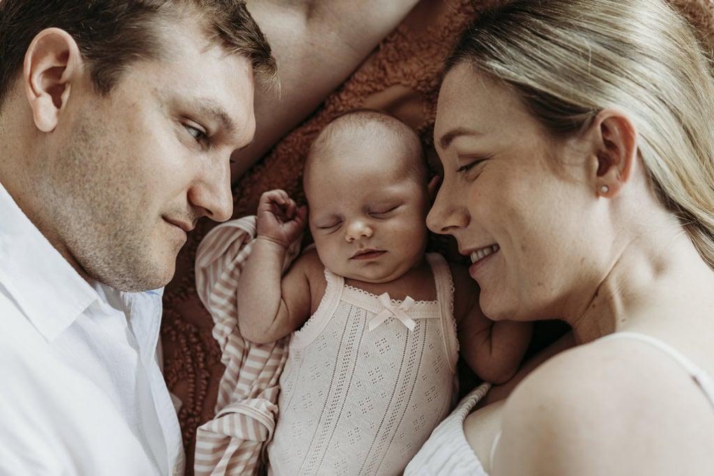 A newborn is asleep as her parents lie down next to her.