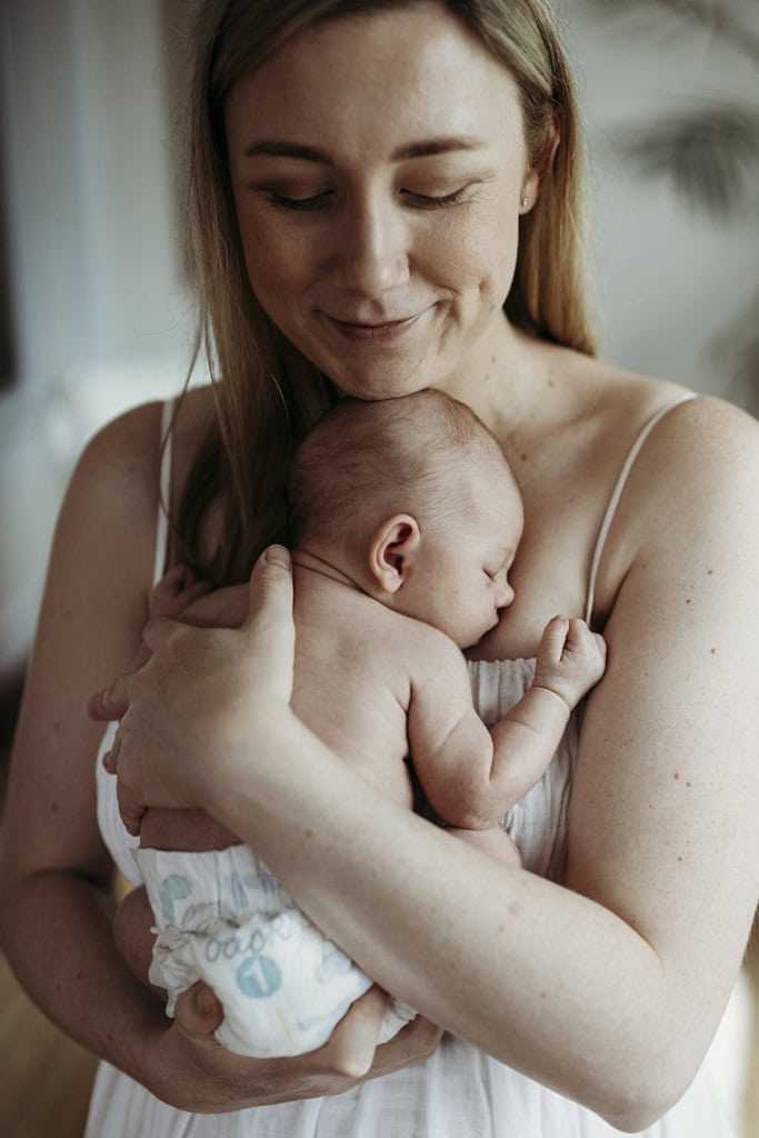 A mother holds her baby against her chest and smiles. 