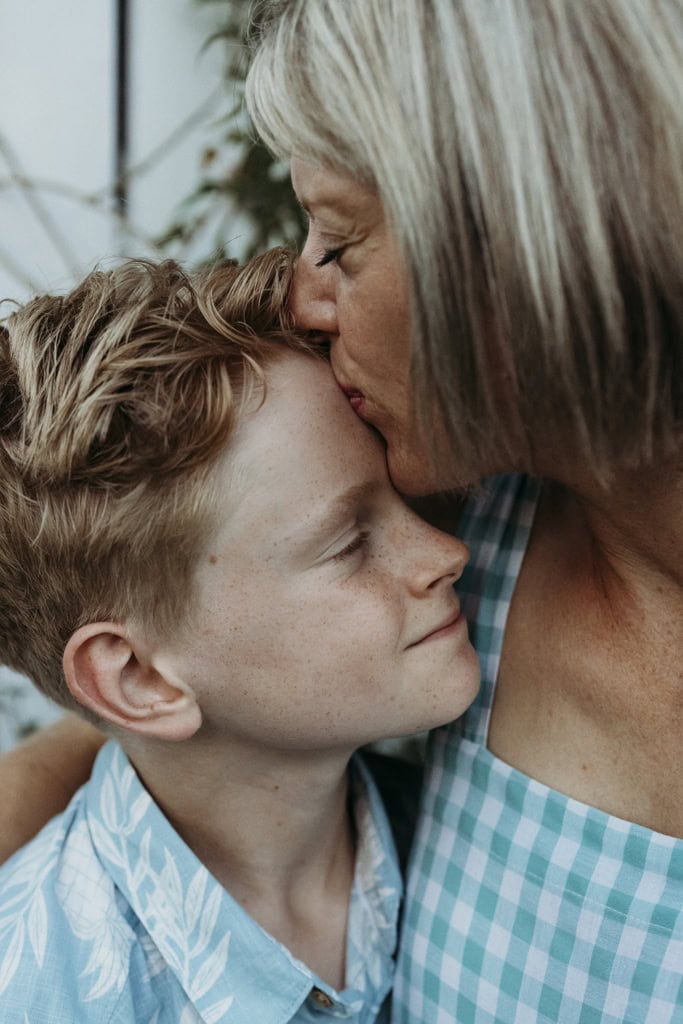 A mother kisses her son on the forehead. Both have their eyes closes and you can feel the emotion from both of them.