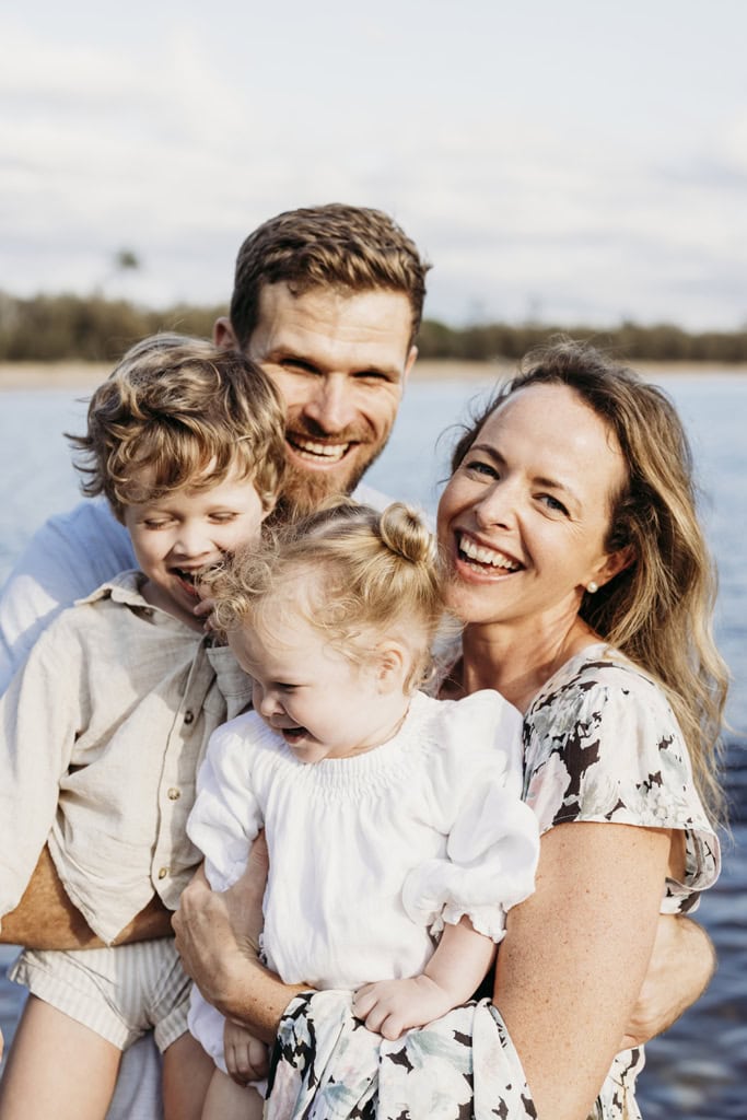 A family of four cuddle and laugh.